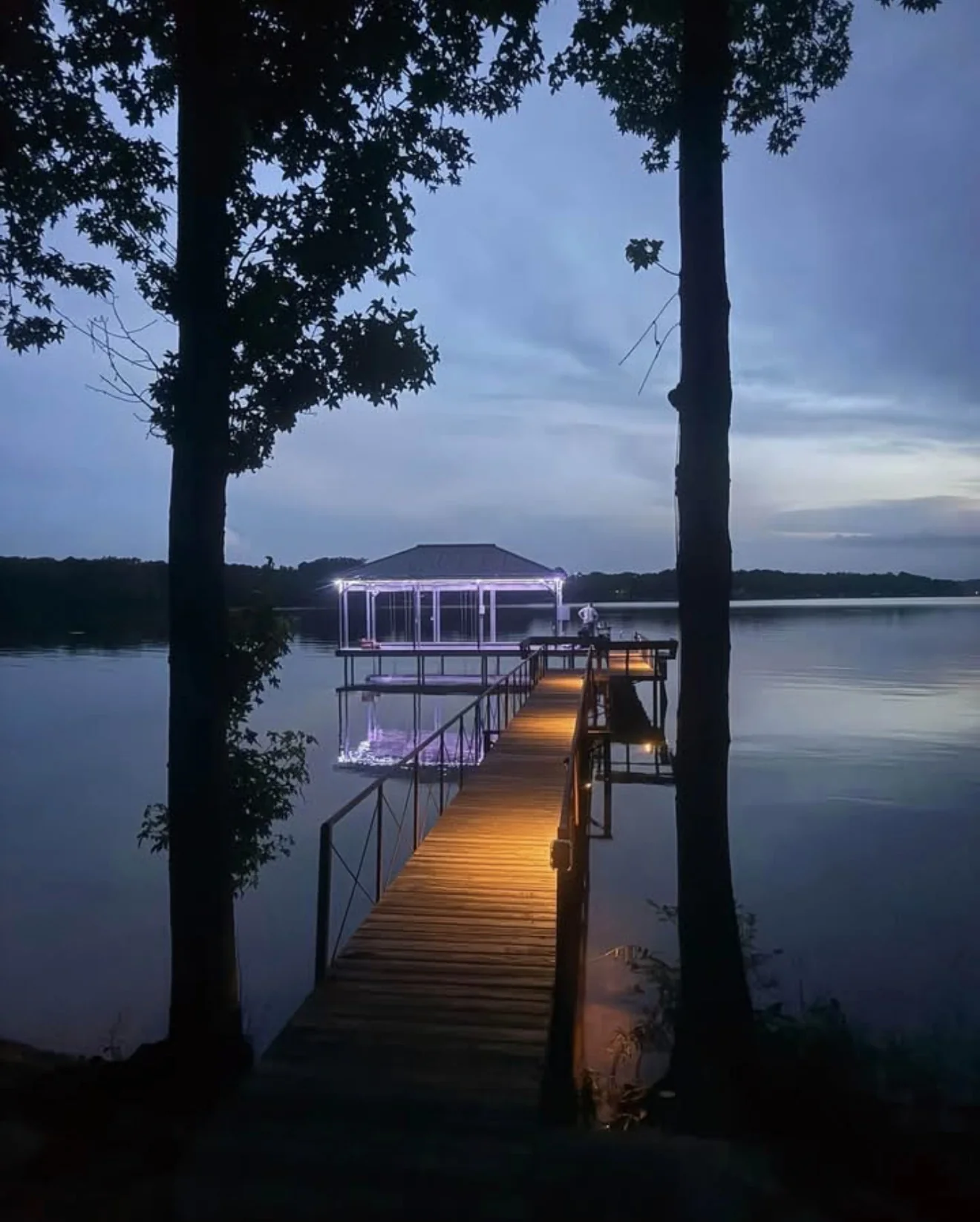 Illuminated dock walkway extending across a lake at dusk